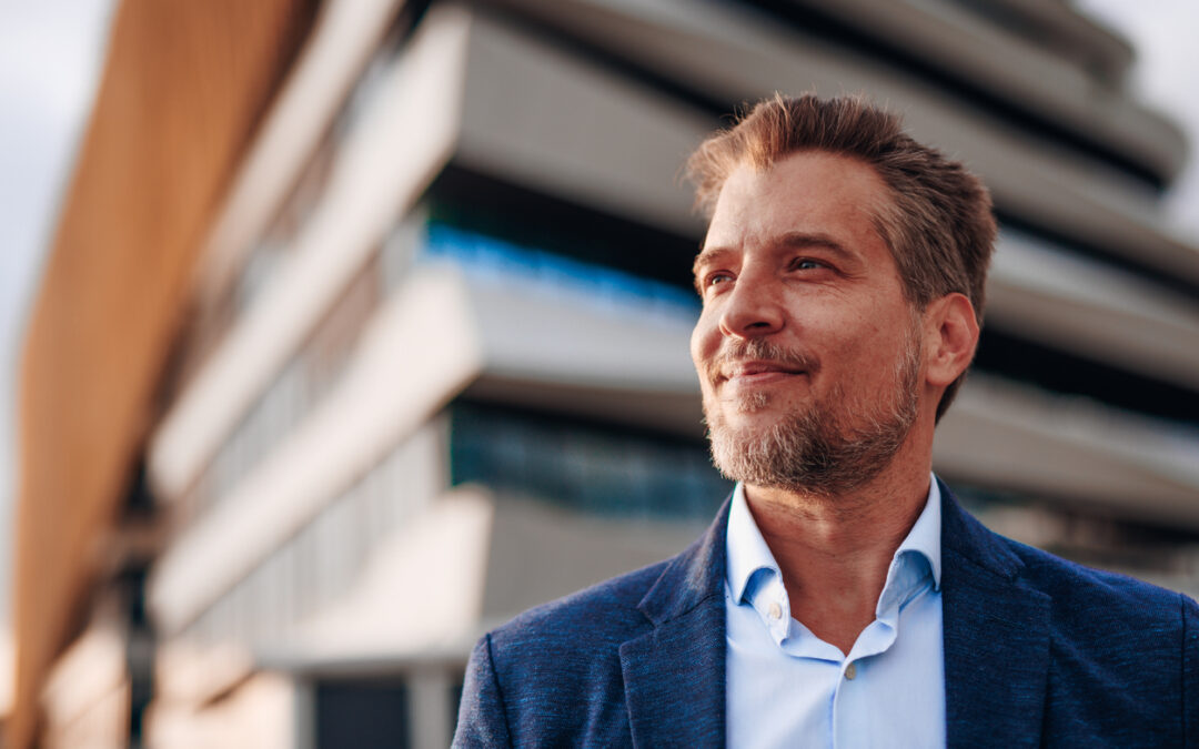 confident businessman looking up at modern building with hope and ambition