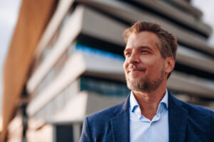 confident businessman looking up at modern building with hope and ambition